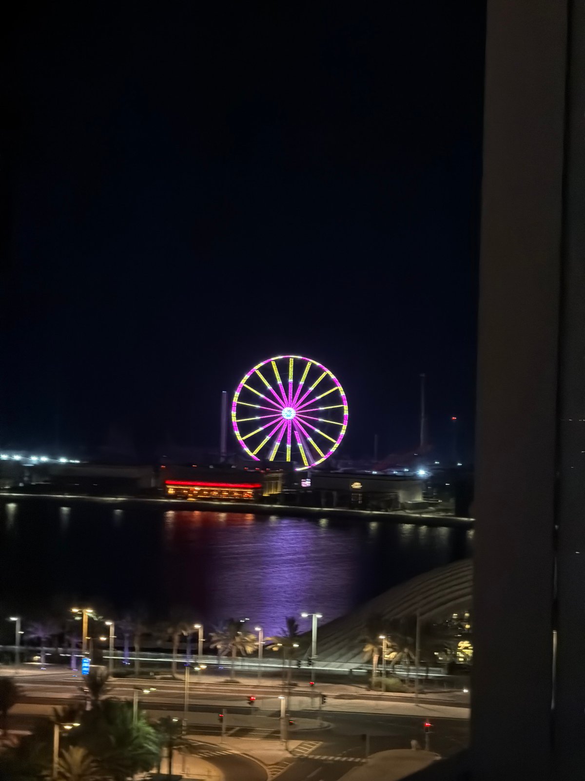Waterfront Ferris wheel lit up at night, multiple angles