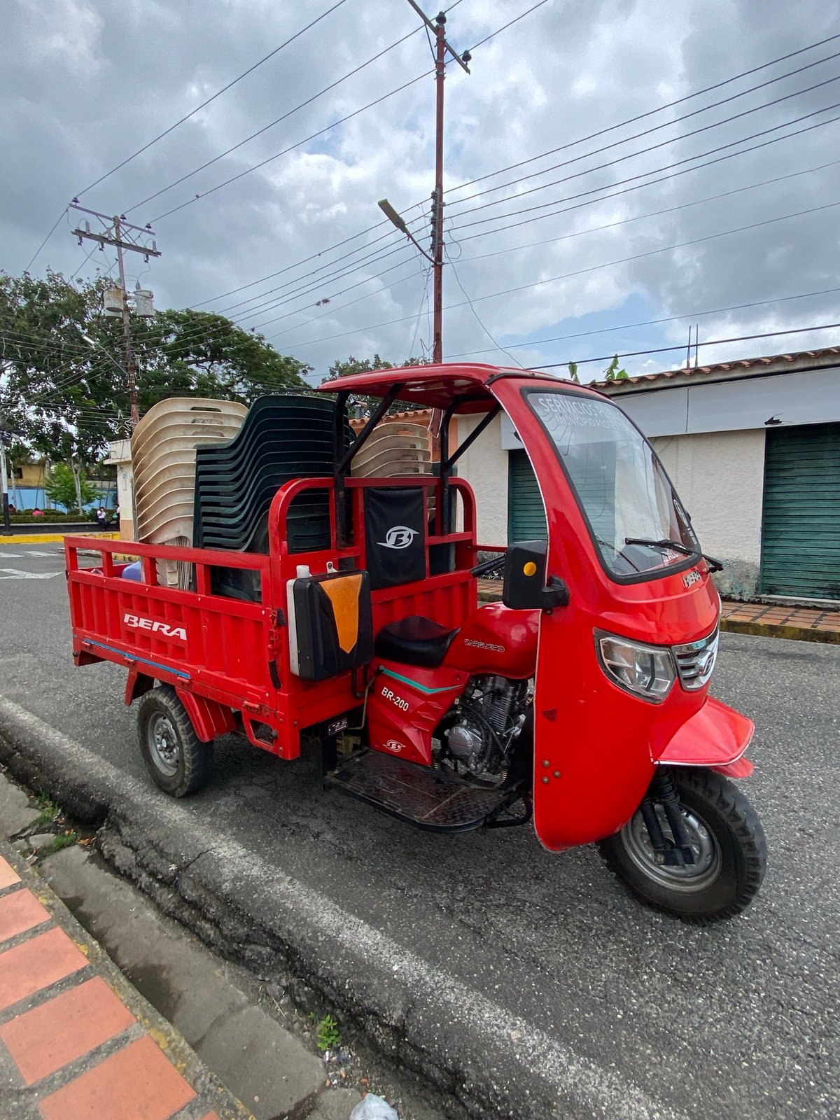 Red three-wheeled taxi, man, baked goods observed in Venezuelan town