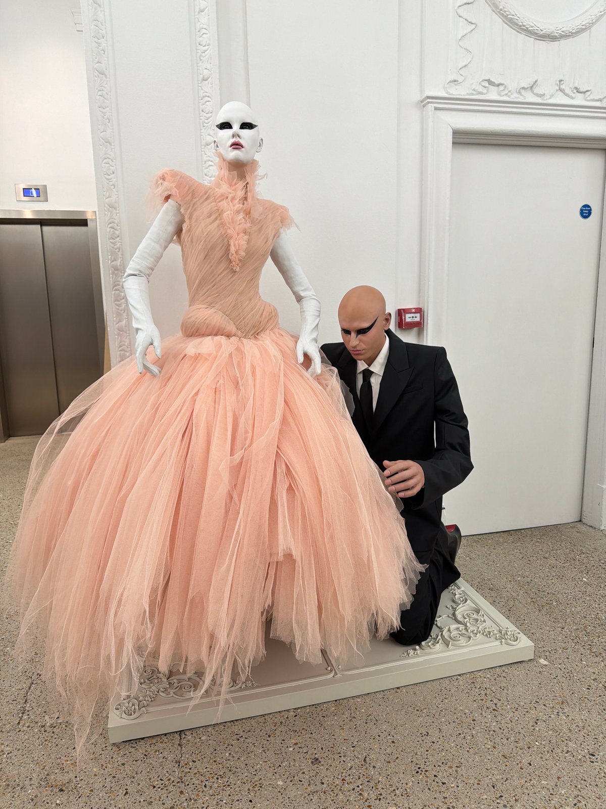 Man adjusts formal mannequin display in London clothing store
