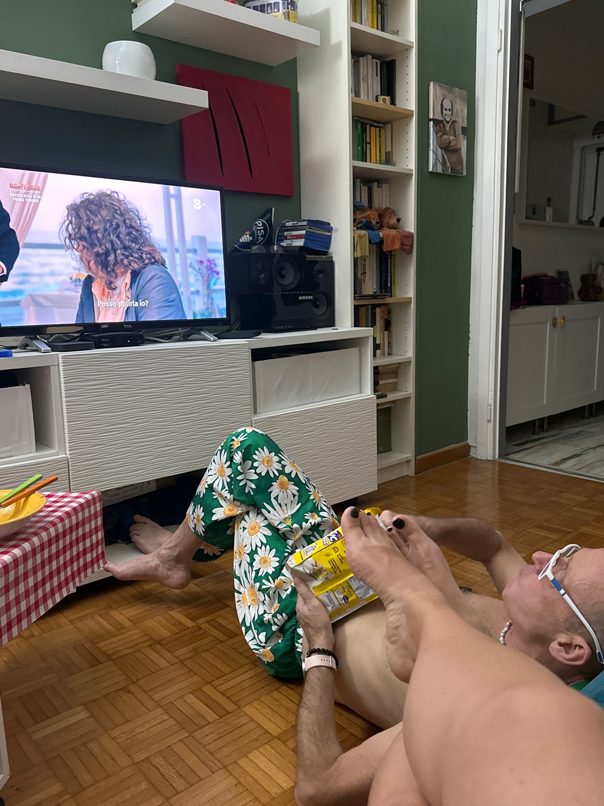 Man in pearl necklace rests on Milan living room floor