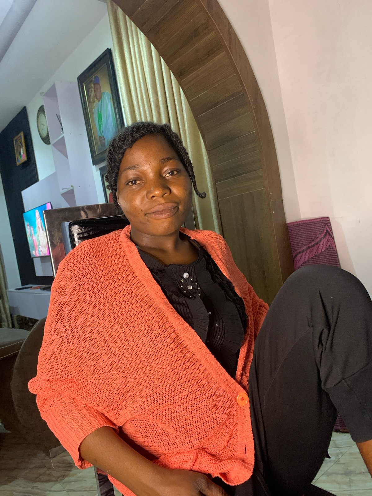 Indoor portrait session in Jos, Nigeria — coral cardigan and braids