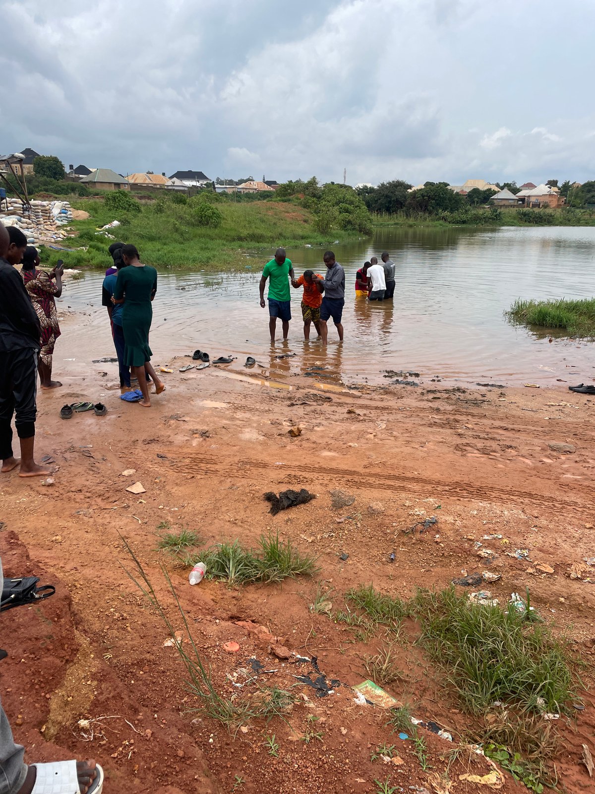 Outdoor baptism service in muddy water near Jos, Nigeria