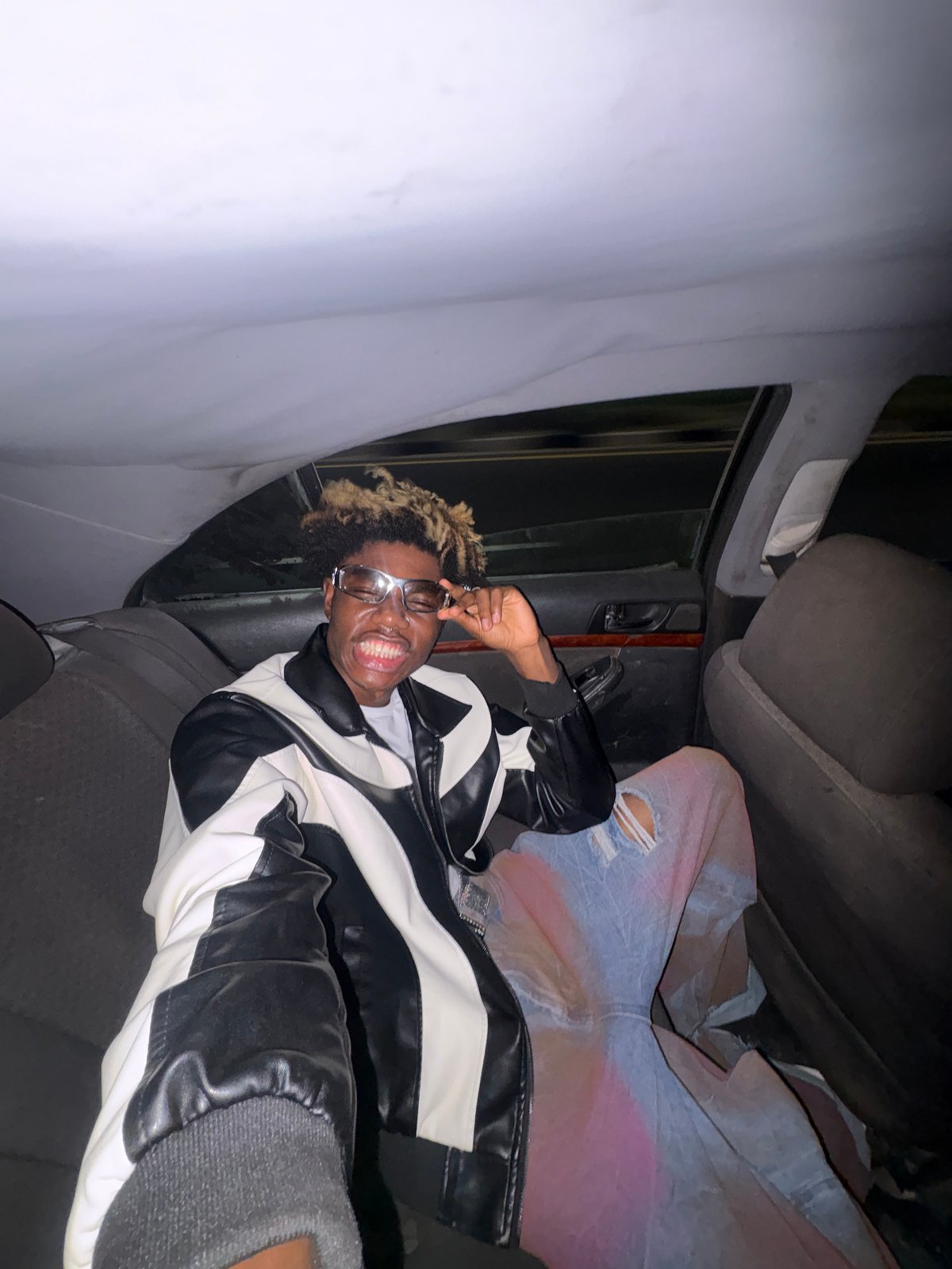 Person in leather jacket photographed in car backseat, Ilado Nigeria