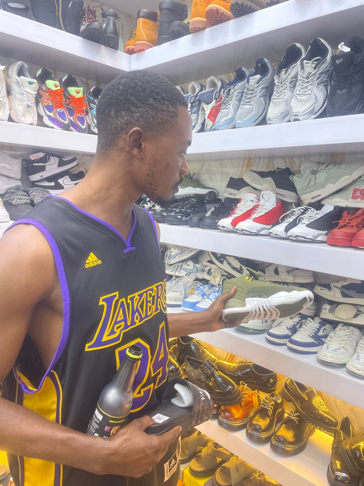 Young men browse shoes while drinking energy drinks in Jos store