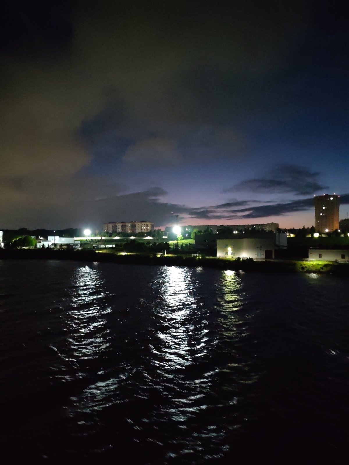 Cherepovets cityscape reflects across Sheksna River at night