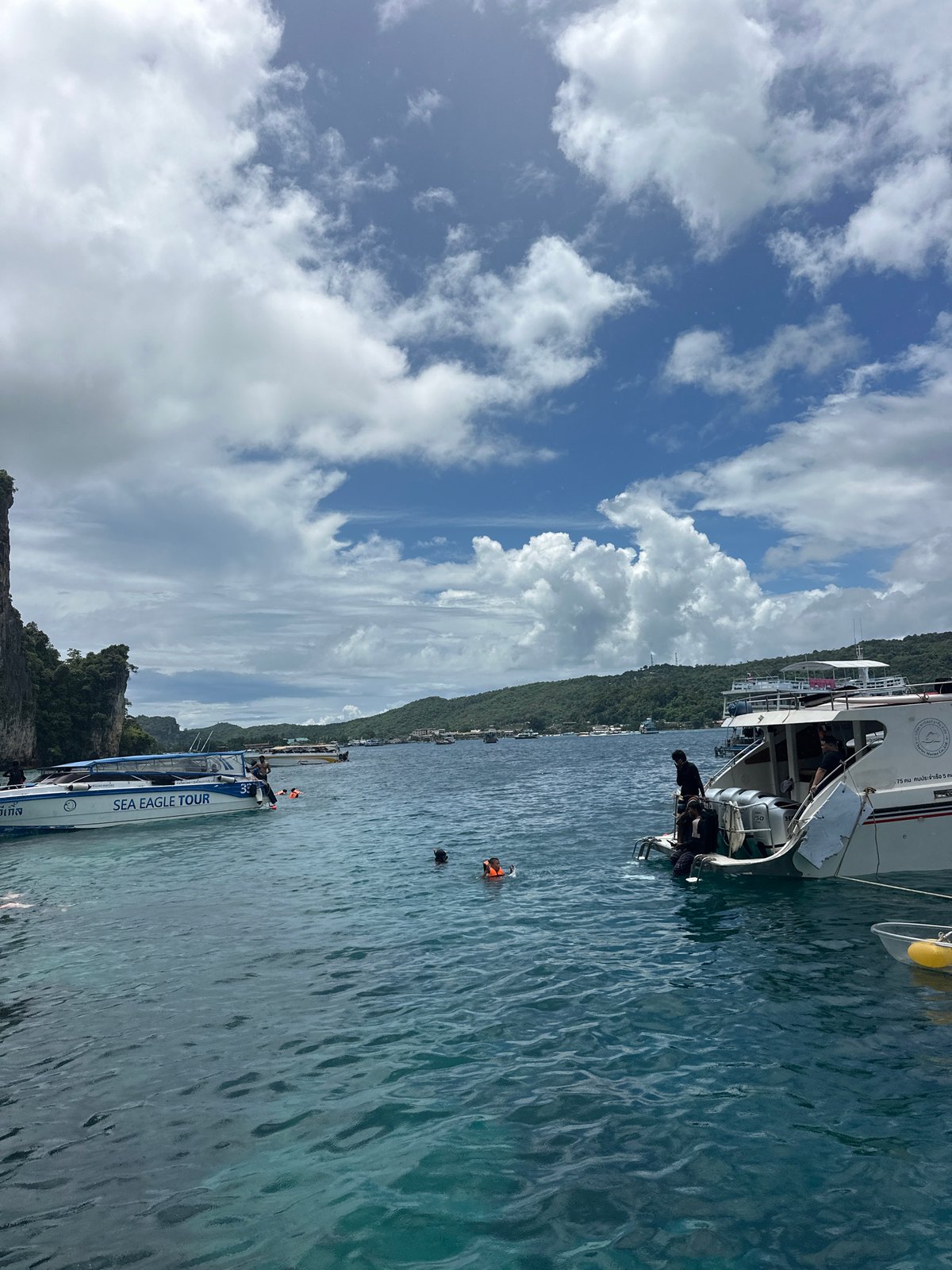 Boats and snorkelers at Haad Hin Khom's limestone coast