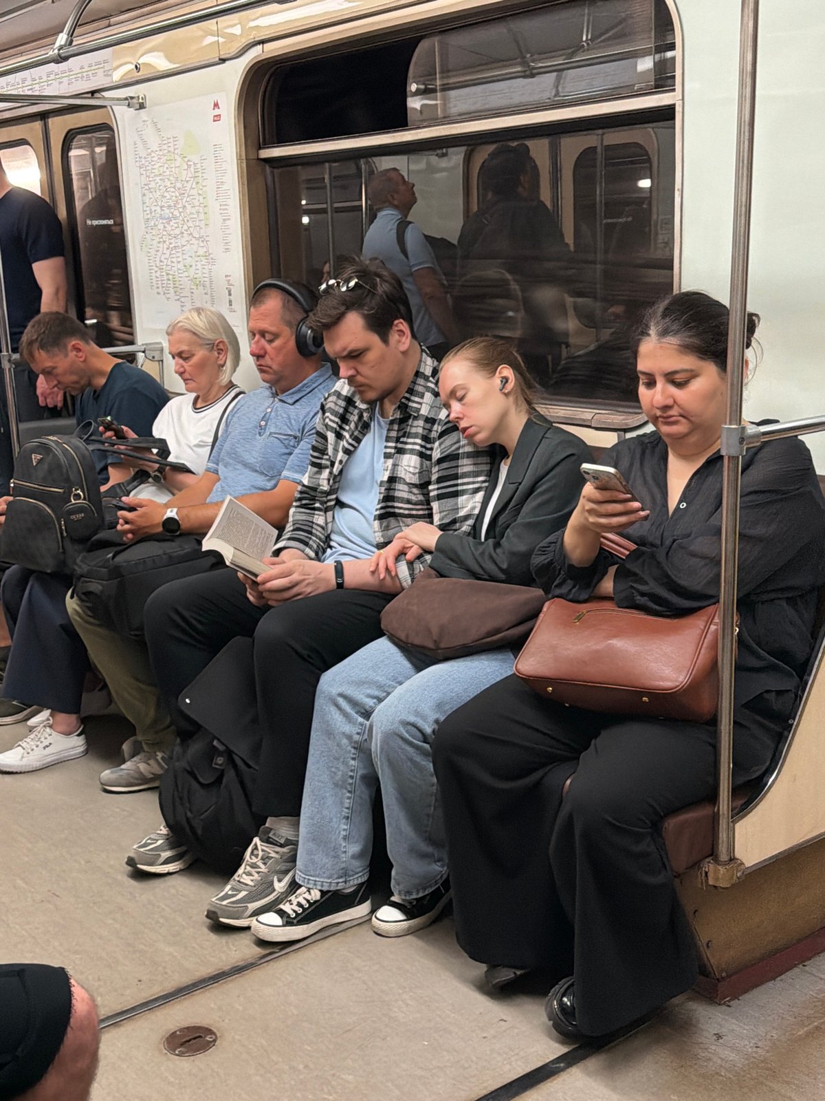 Passengers on the Moscow Metro, phones out, mid-ride.