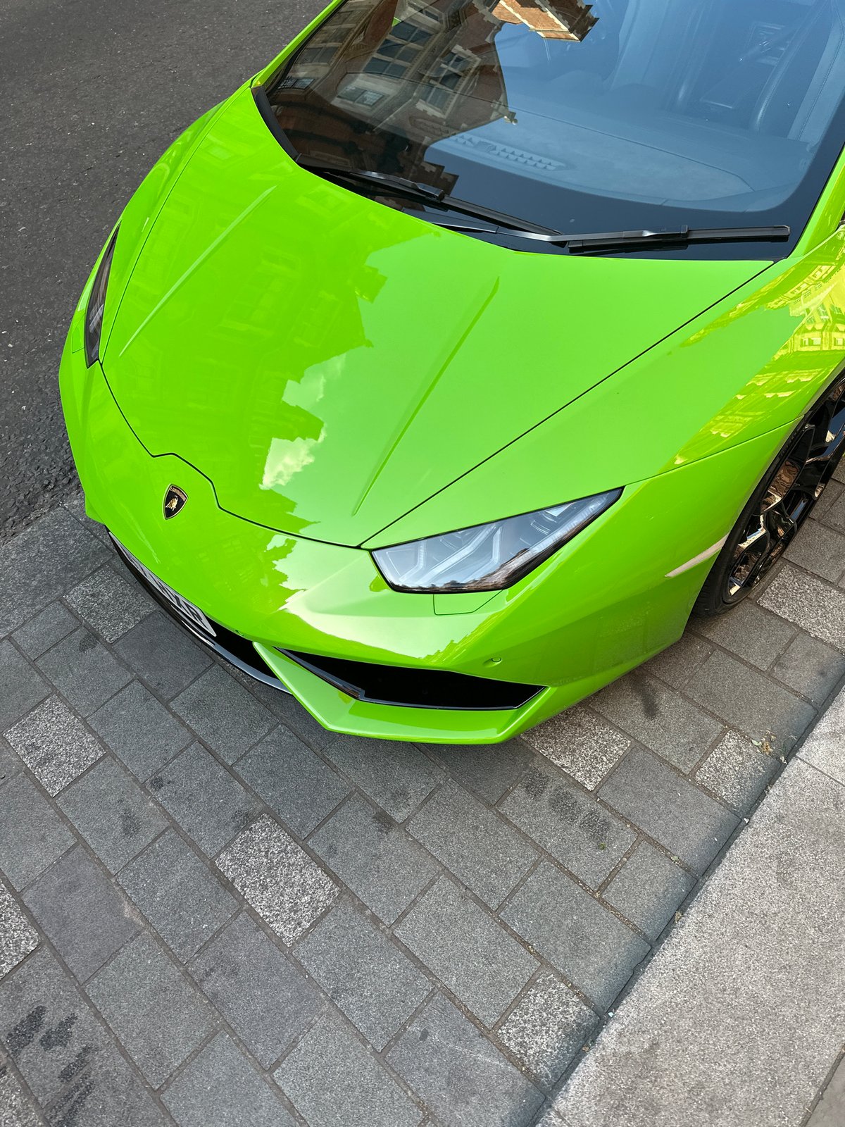 Luxury supercars gather on London cobblestone streets near Hepburn plaque