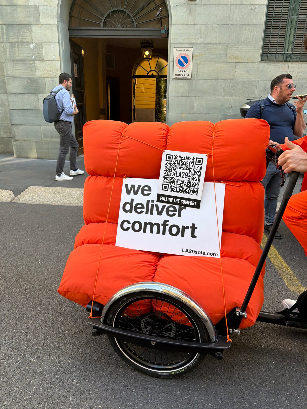 Orange sofa transported through Milan streets in daylight