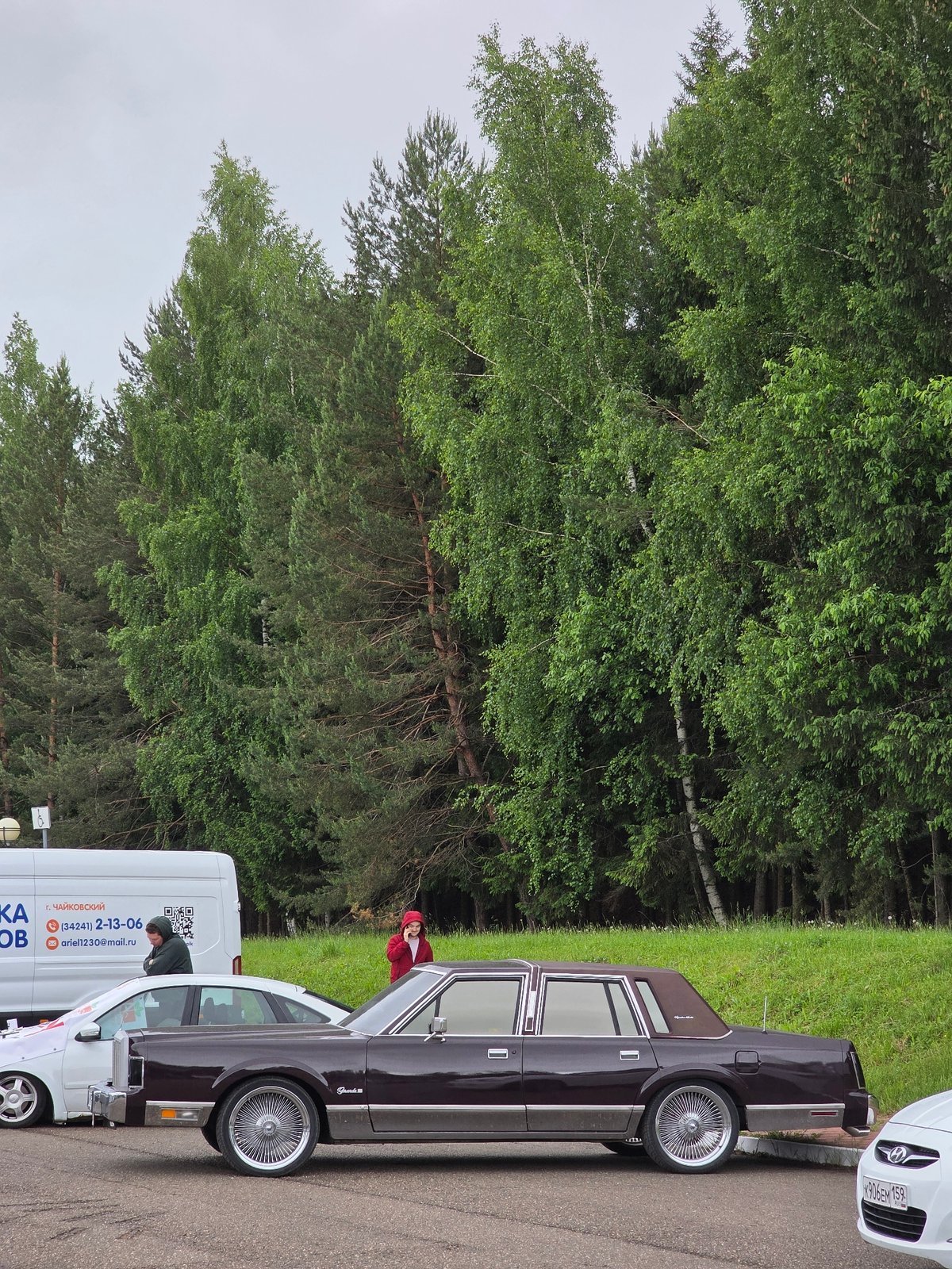 Modified car gathering under overcast skies after rain