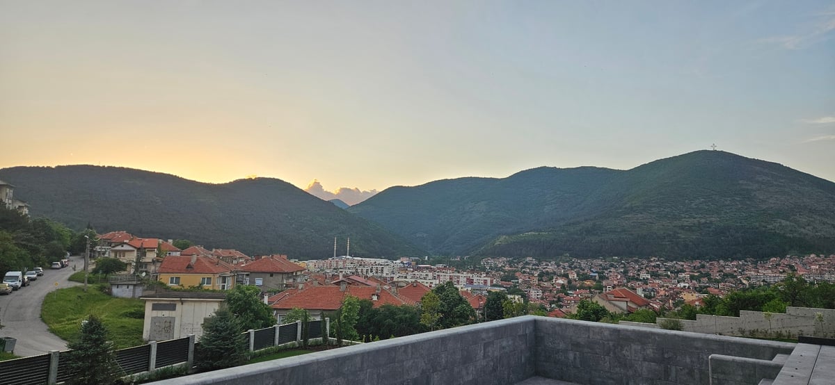Evening scenes captured across mountainous town with illuminated cross