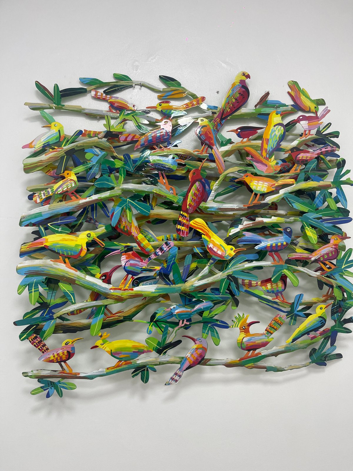 Colorful bird and tree artwork displayed on white wall