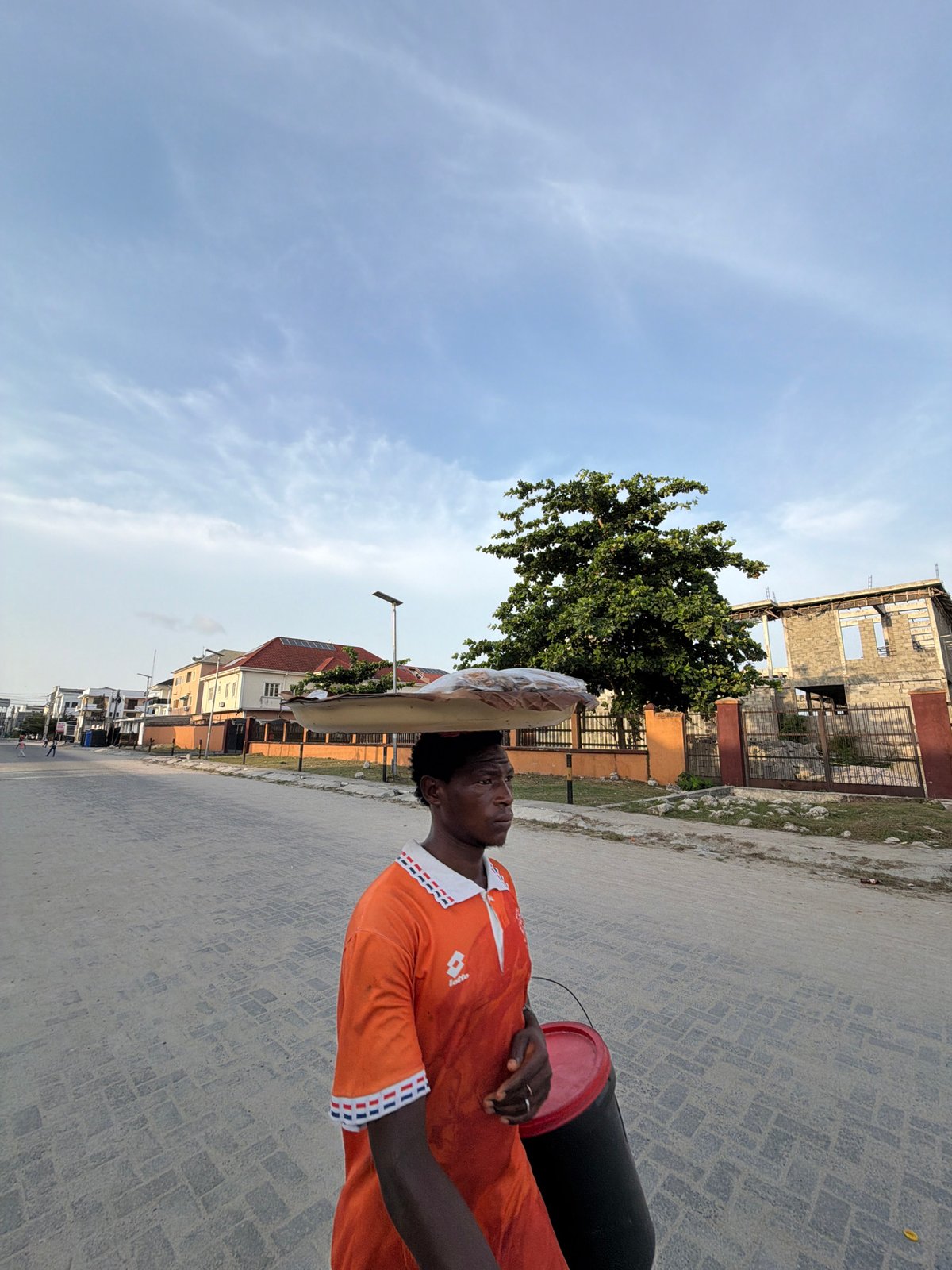 Man carries containers on head through Igboefon street