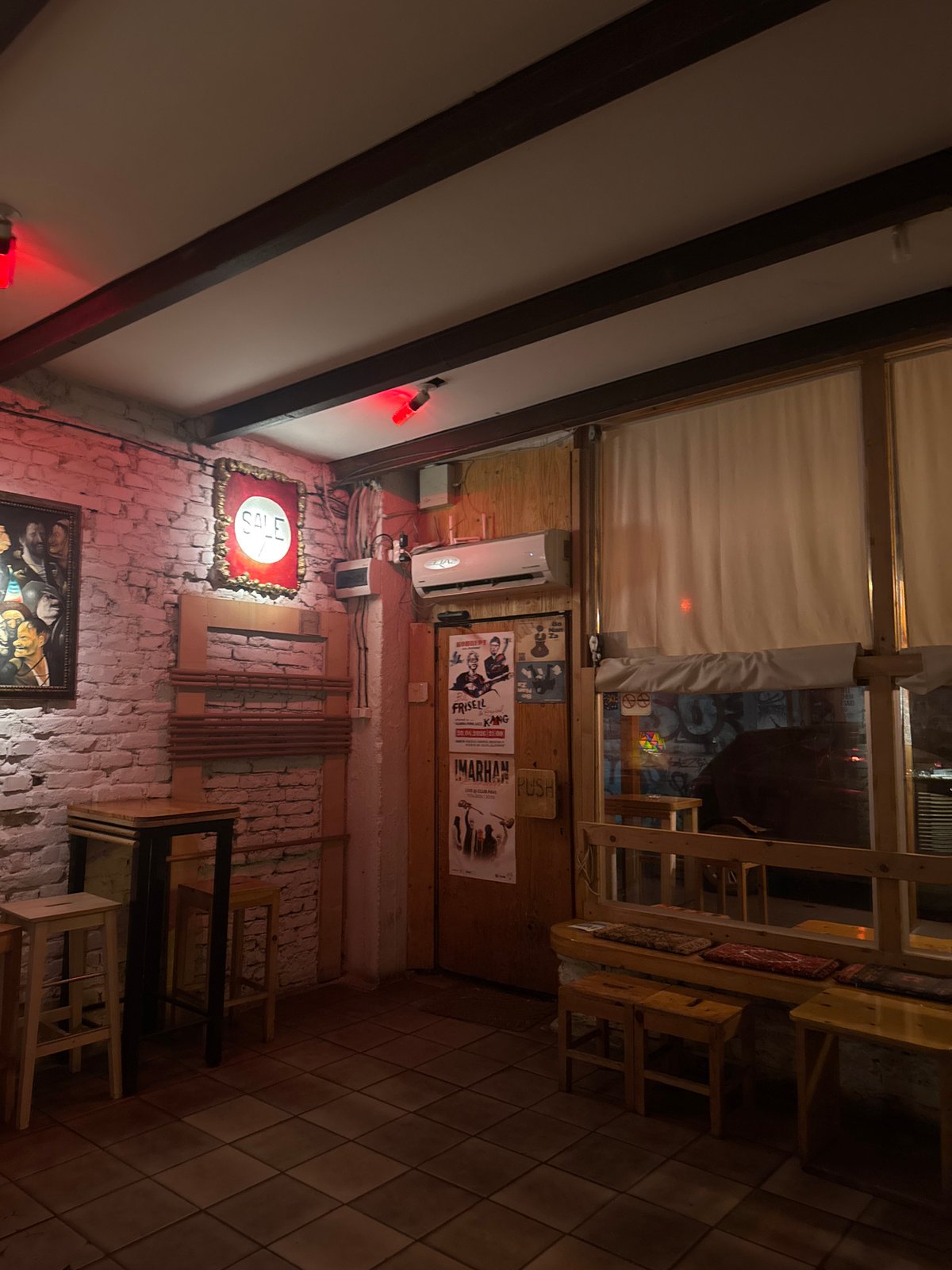 Person photographed at dimly lit Sofia establishment wearing yellow sunglasses
