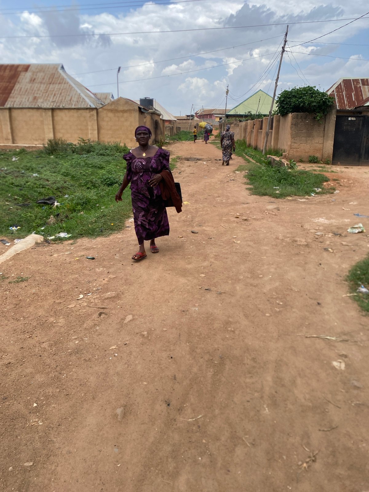 Woman carries bundle on dirt road in Bukuru