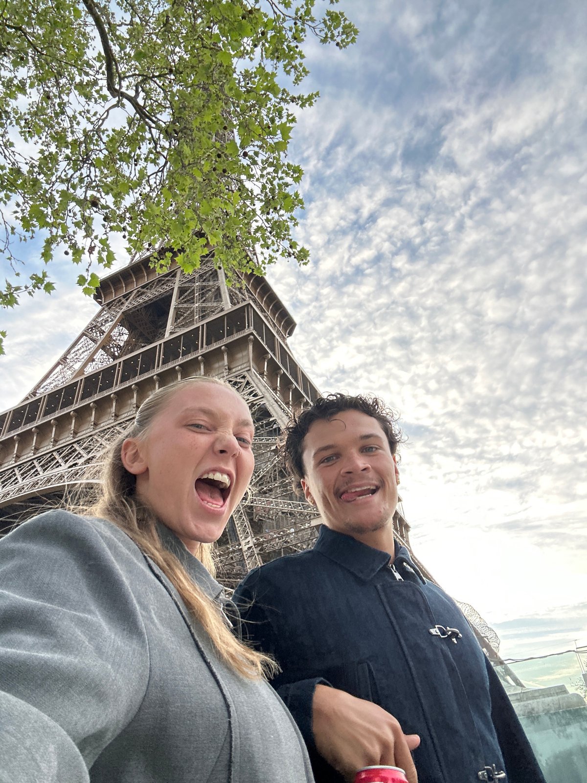 Tourist photographs Eiffel Tower under cloudy Paris skies