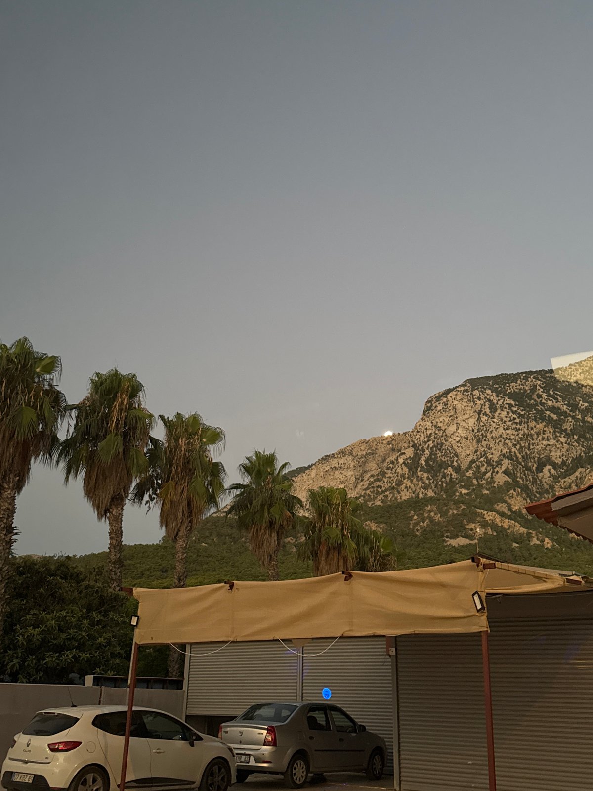 Late-night Kemer: moon over mountains, palms, and quiet streets