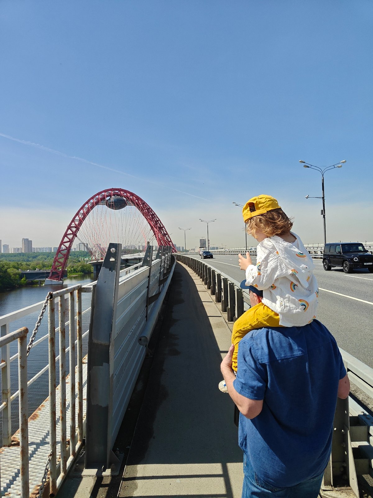 Father carries child on shoulders across Moscow bridge