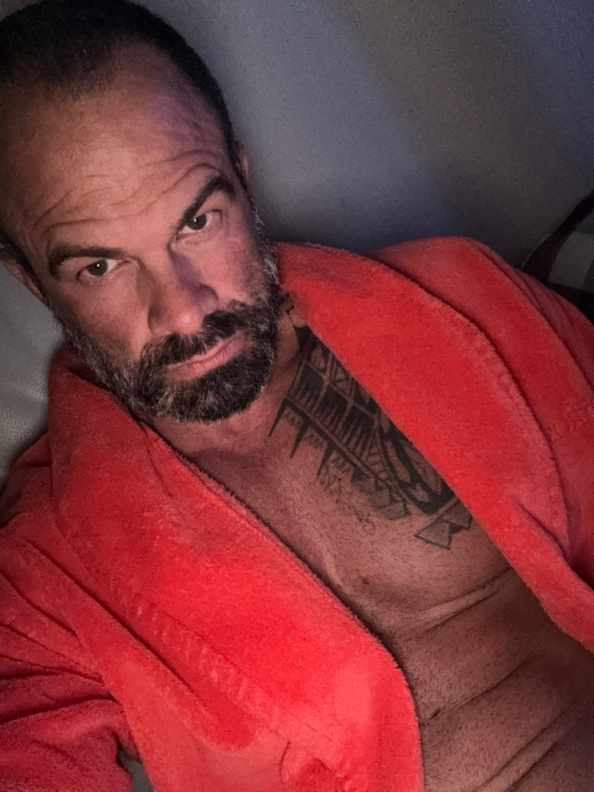 Man in orange bathrobe filmed reclining indoors in Belgium