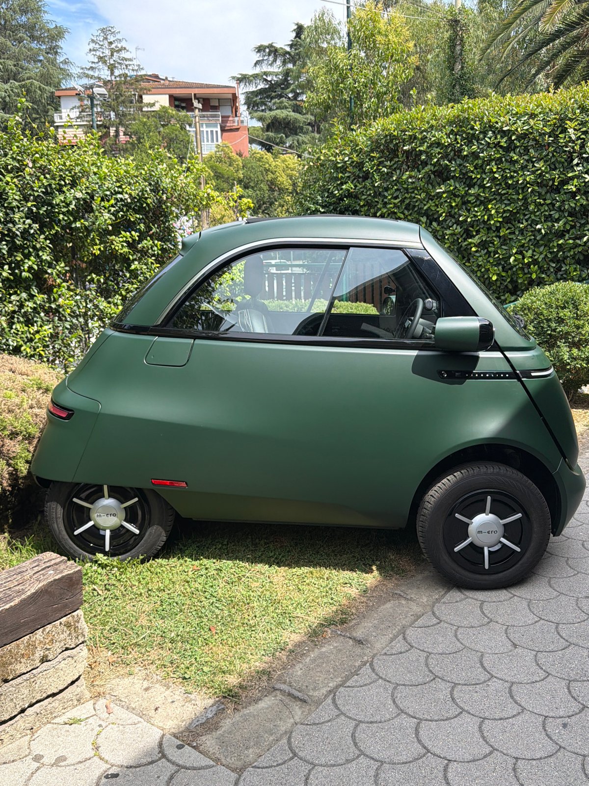 M-cro electric three-wheeler parked along a Rome walkway