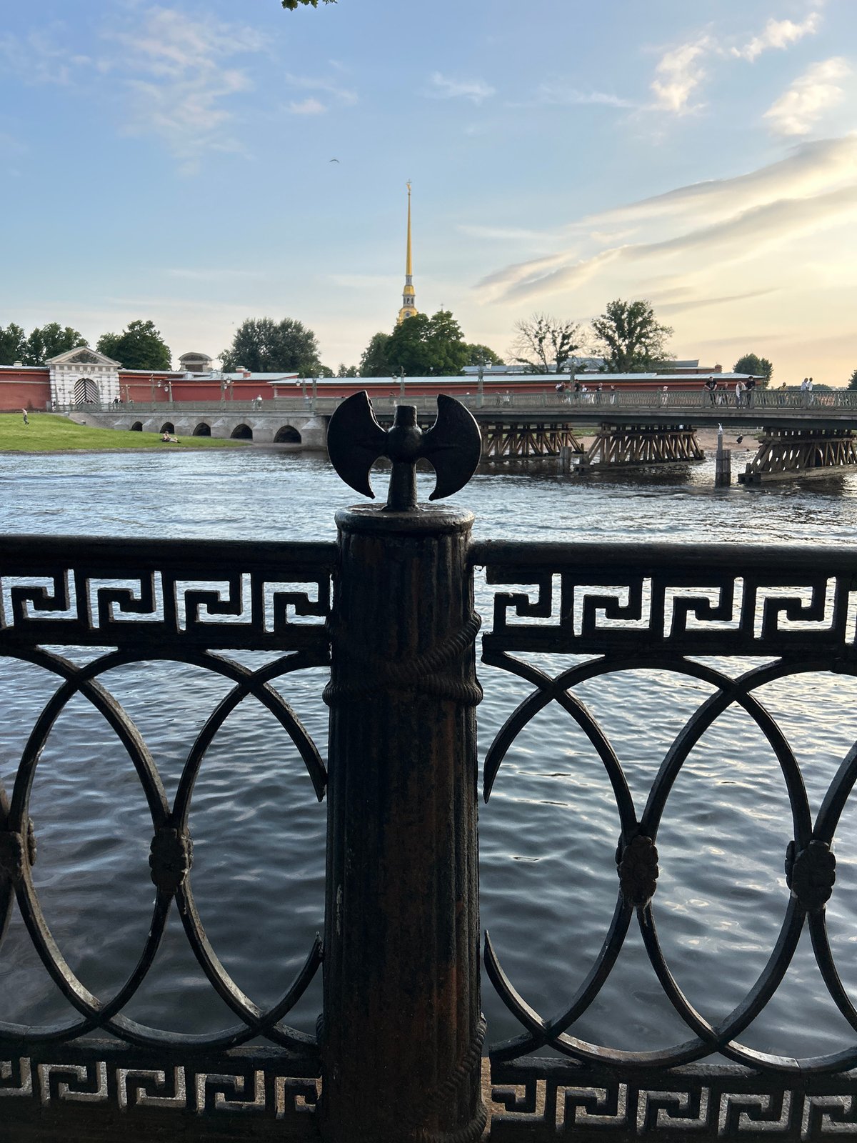 Golden hour along a European riverfront with boats, blooms, and snacks