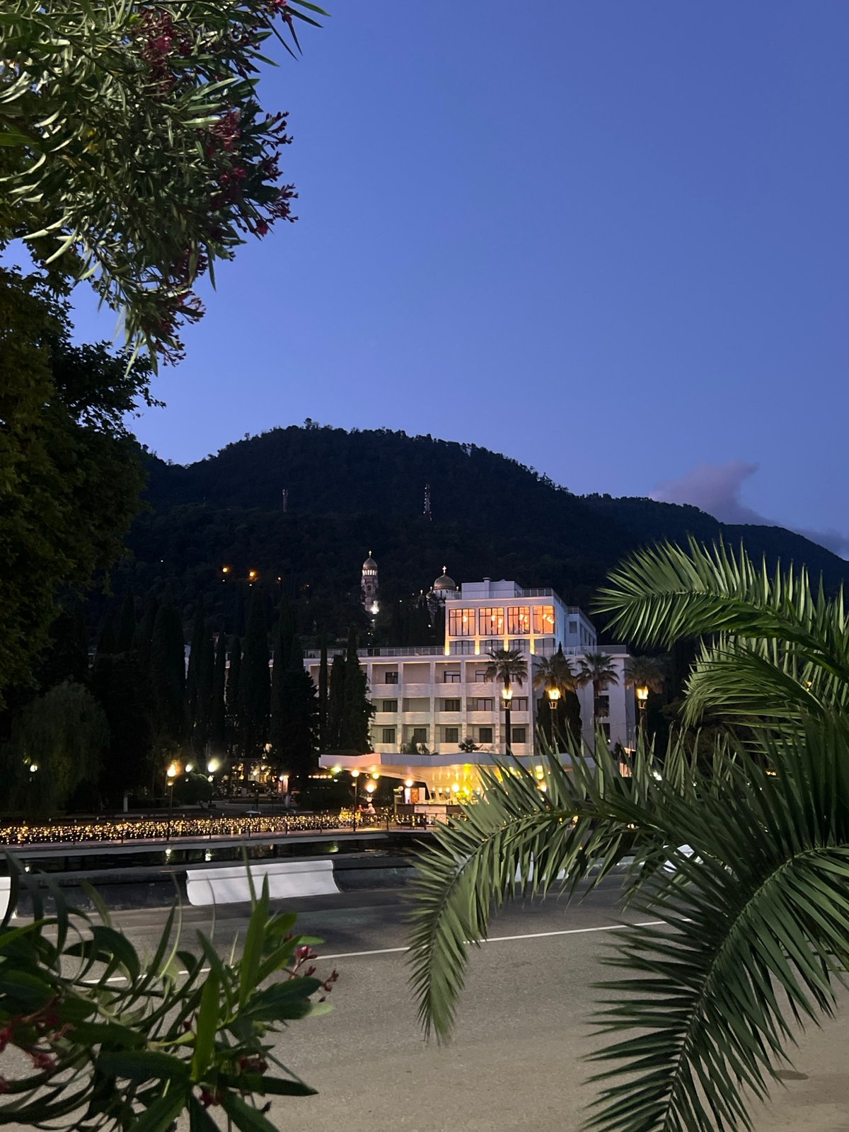 Twilight at a waterfront resort with rides, lights, and Georgian food