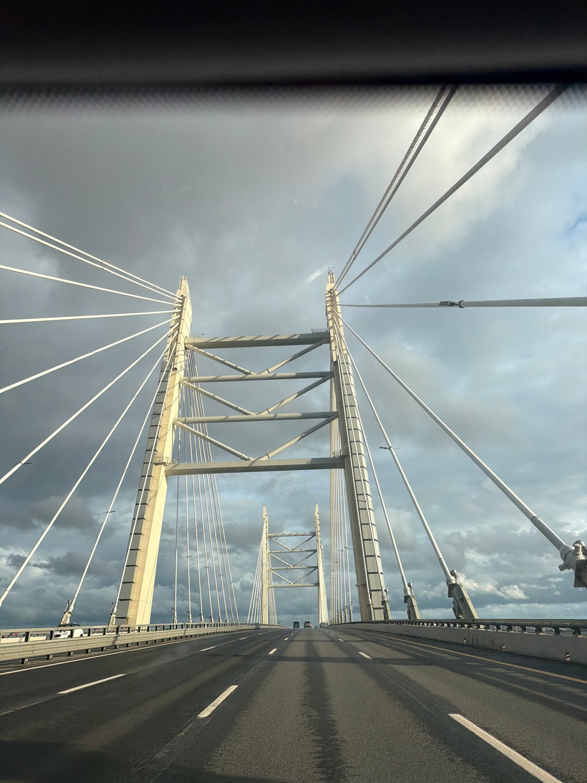 On the road across a cable-stayed bridge under cloudy skies