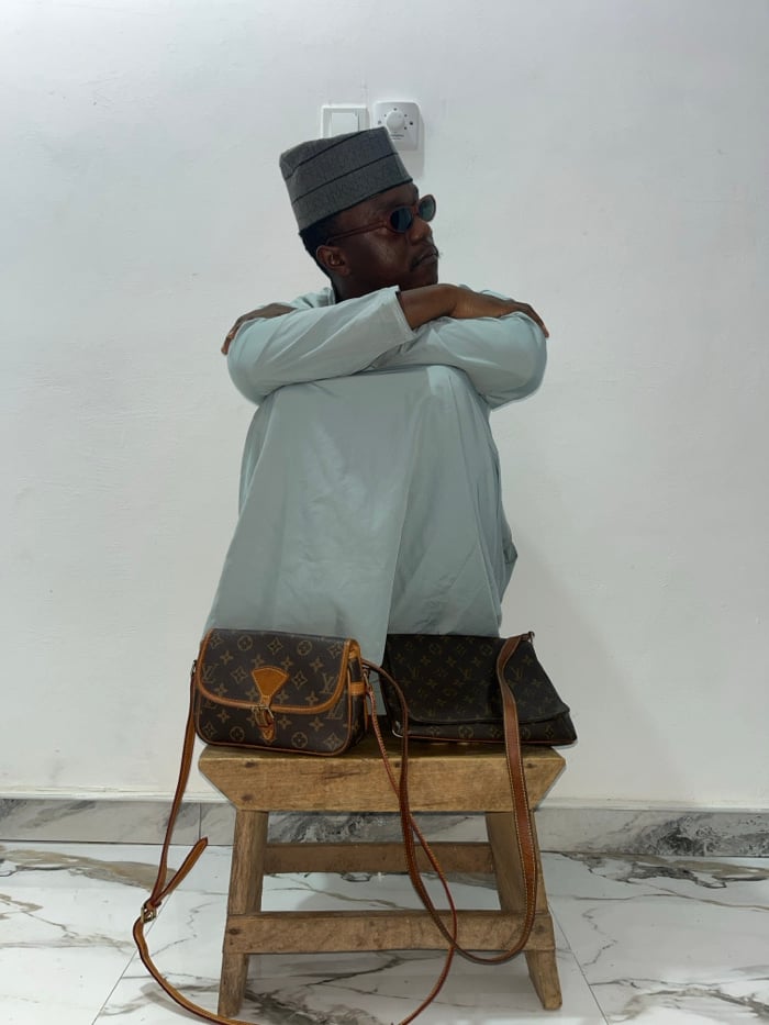 Man poses with luxury bags, reads magazines in Ghana
