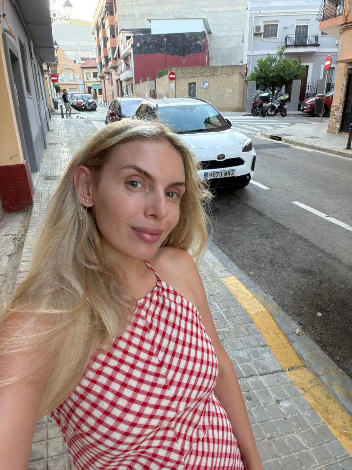 Selfies and street photos along a Valencia sidewalk at dusk