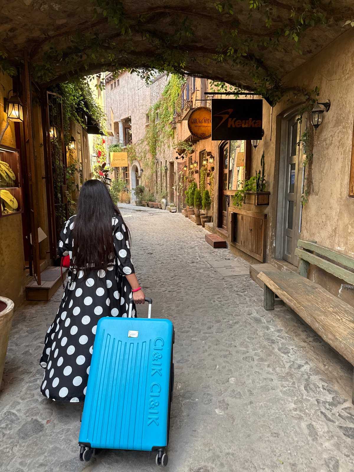 Woman with suitcase walks historic streets in Domingo Arenas