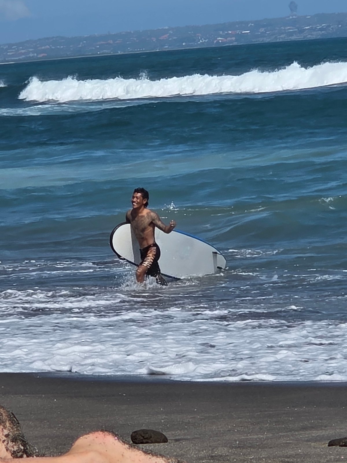 Morning at North Kuta's black sand beach: surfers, families, and shoreline views