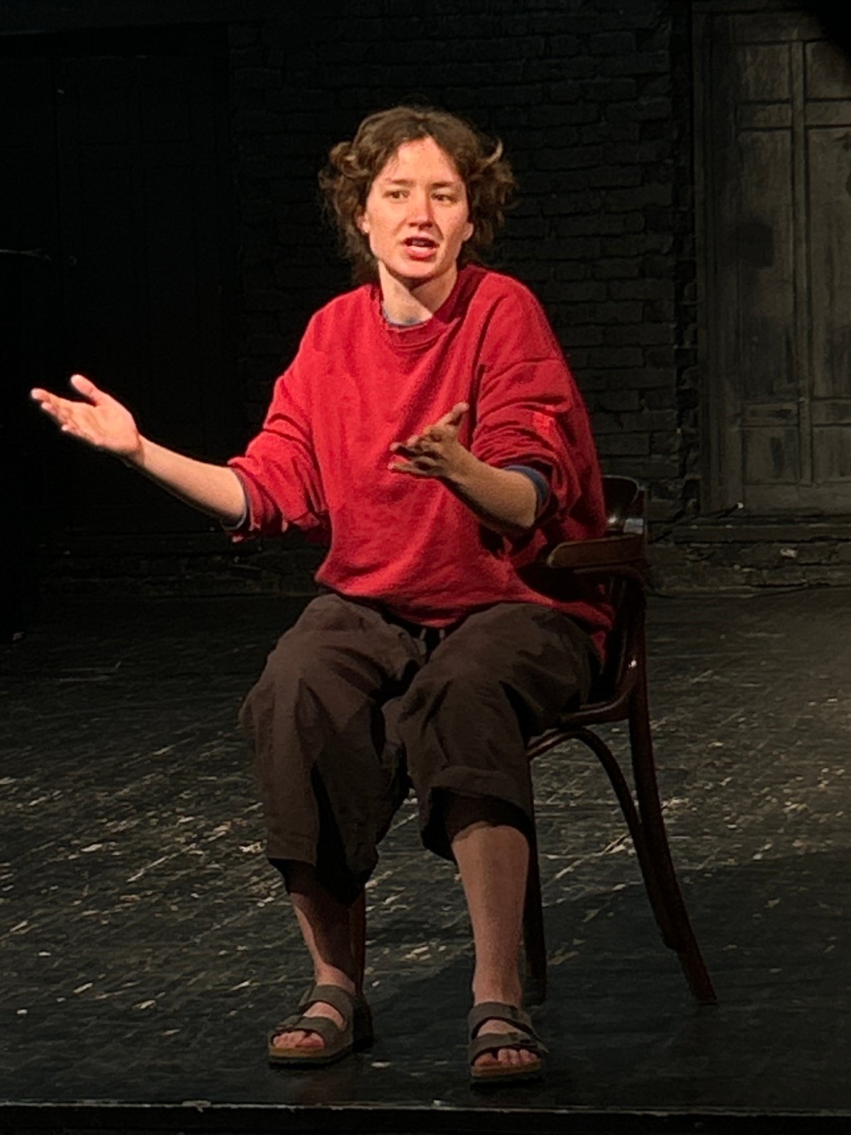 Solo theatrical performance captured on intimate brick-walled stage