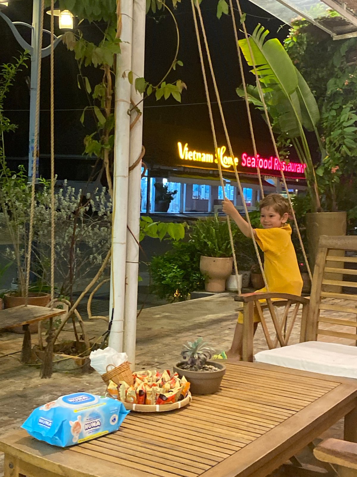 Kids on swings at a casual outdoor restaurant spot in Vietnam