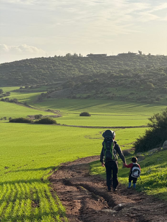 Family group walks muddy farm path in Israeli countryside