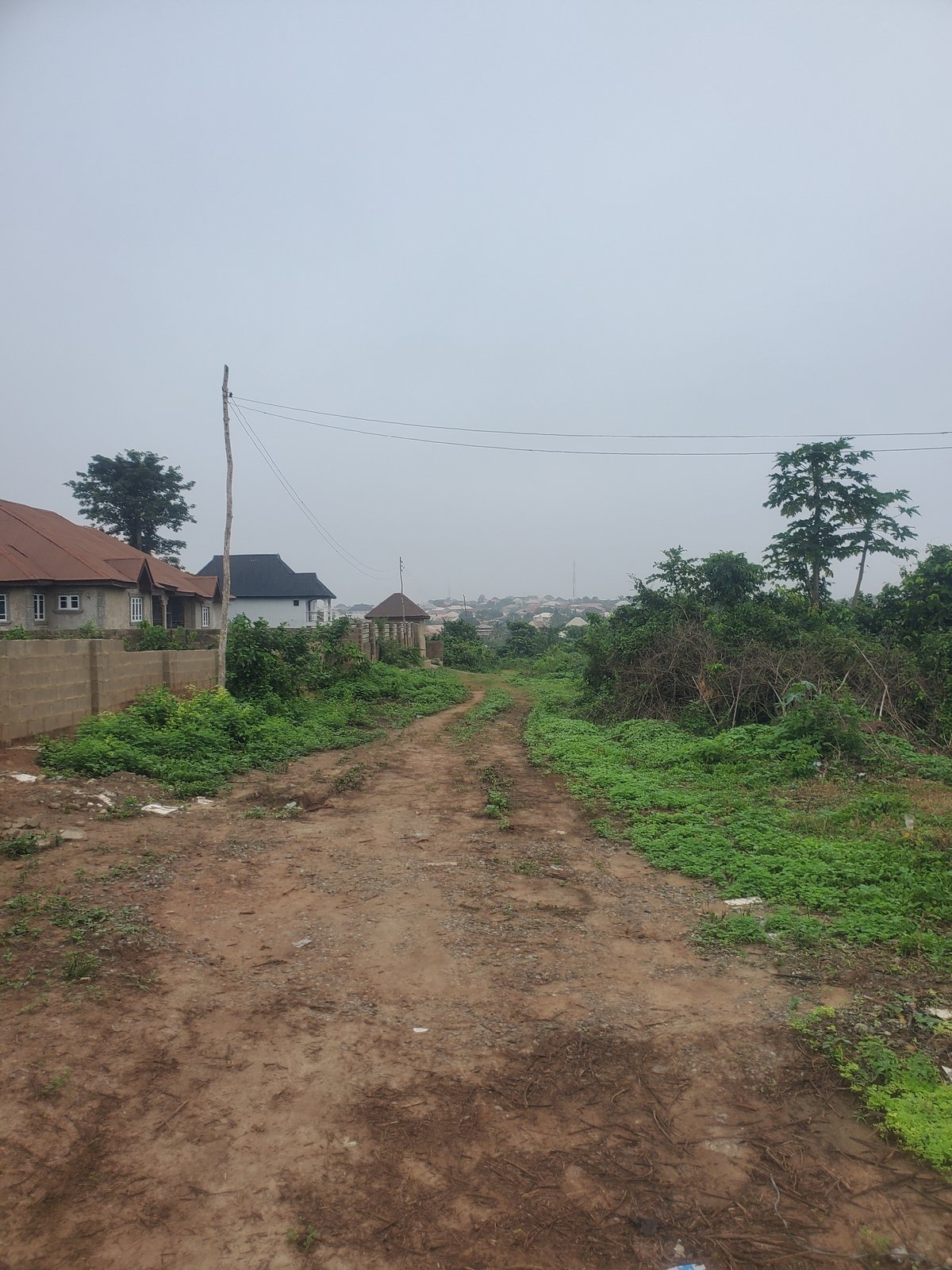 Construction and older buildings sit side by side along a dirt road