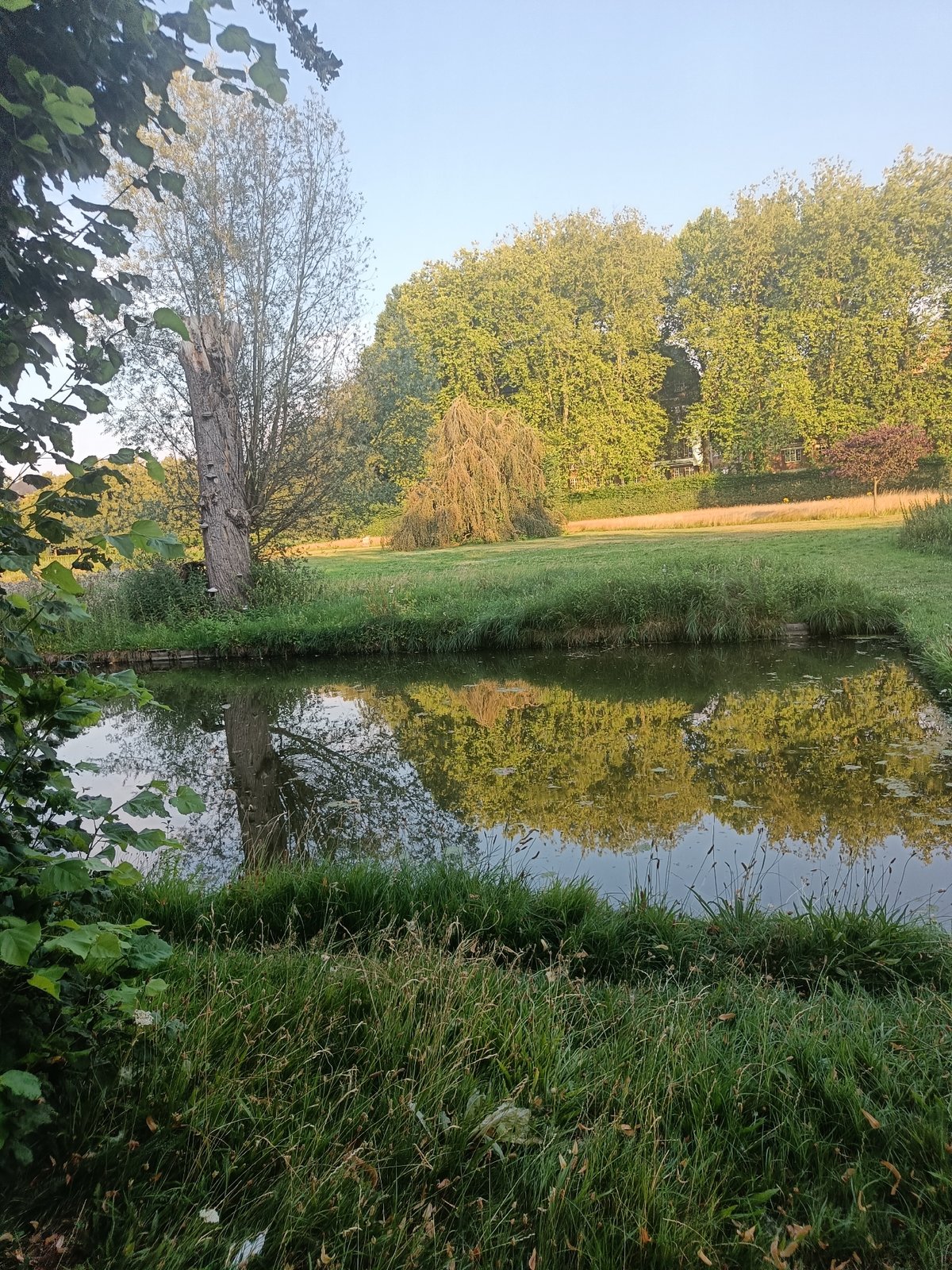 Historic brick building, canal, and park grounds on a summer afternoon