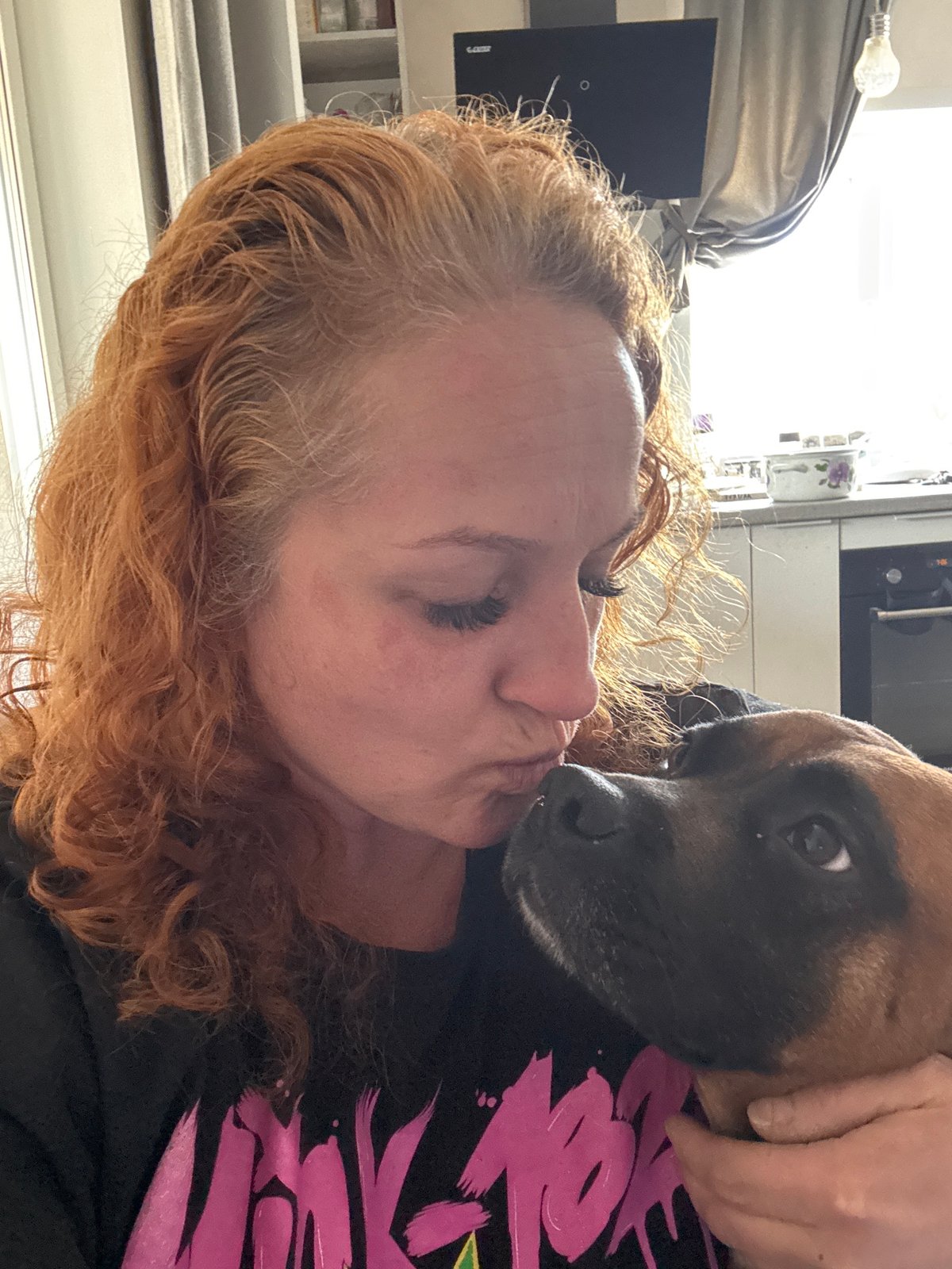 Woman shares tender moments with pet dog indoors
