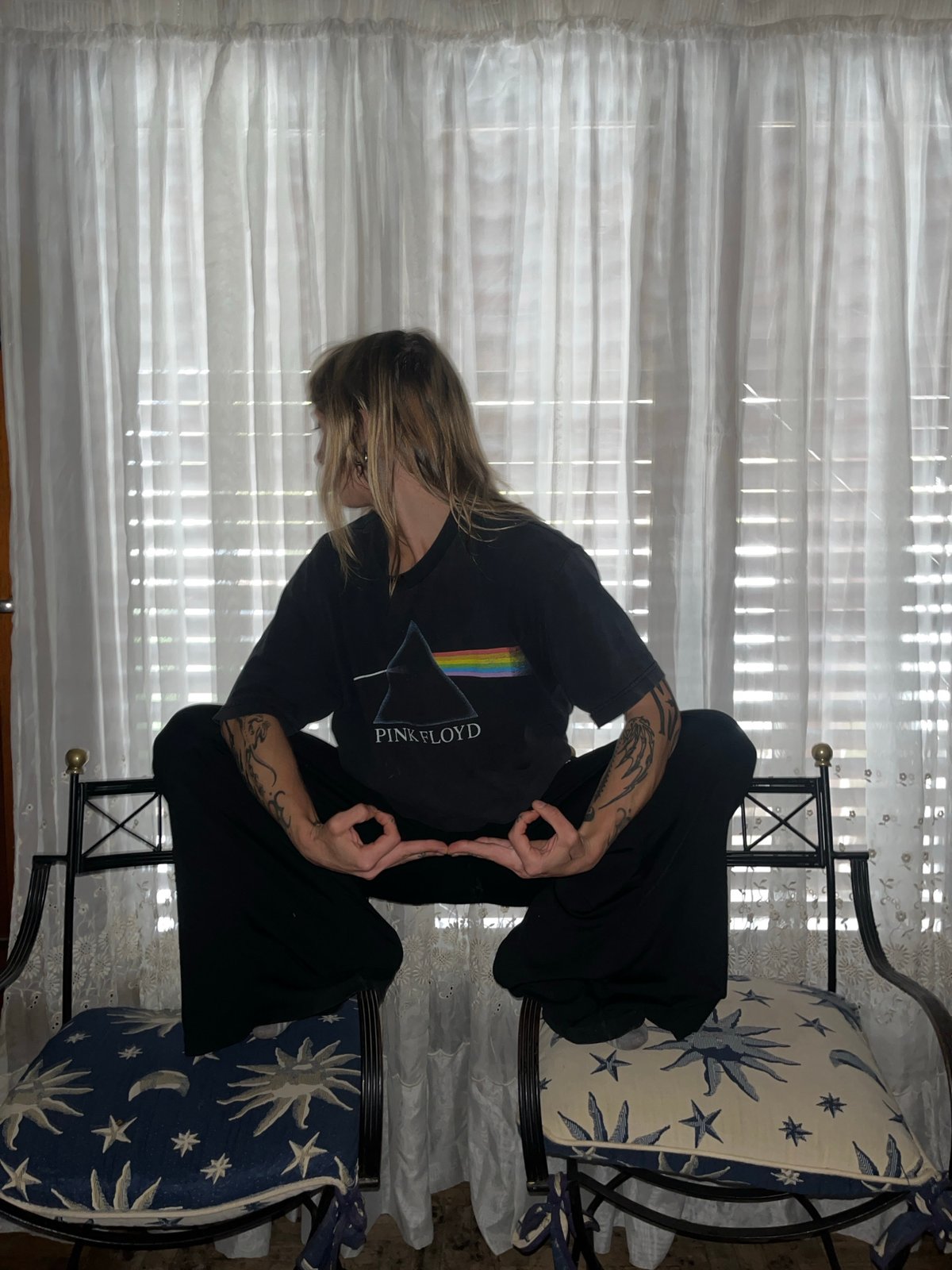 Person in Pink Floyd shirt makes OK gesture by window