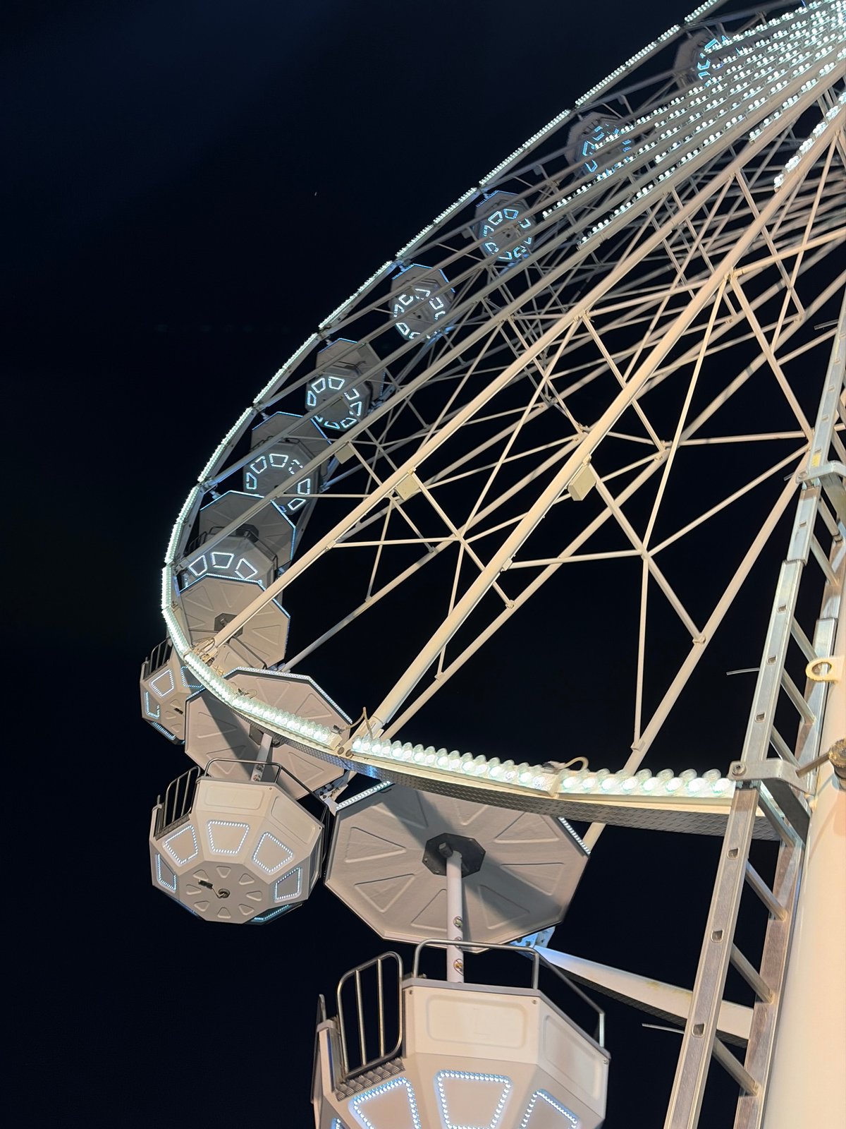Ferris wheel glows with white and blue lights at night