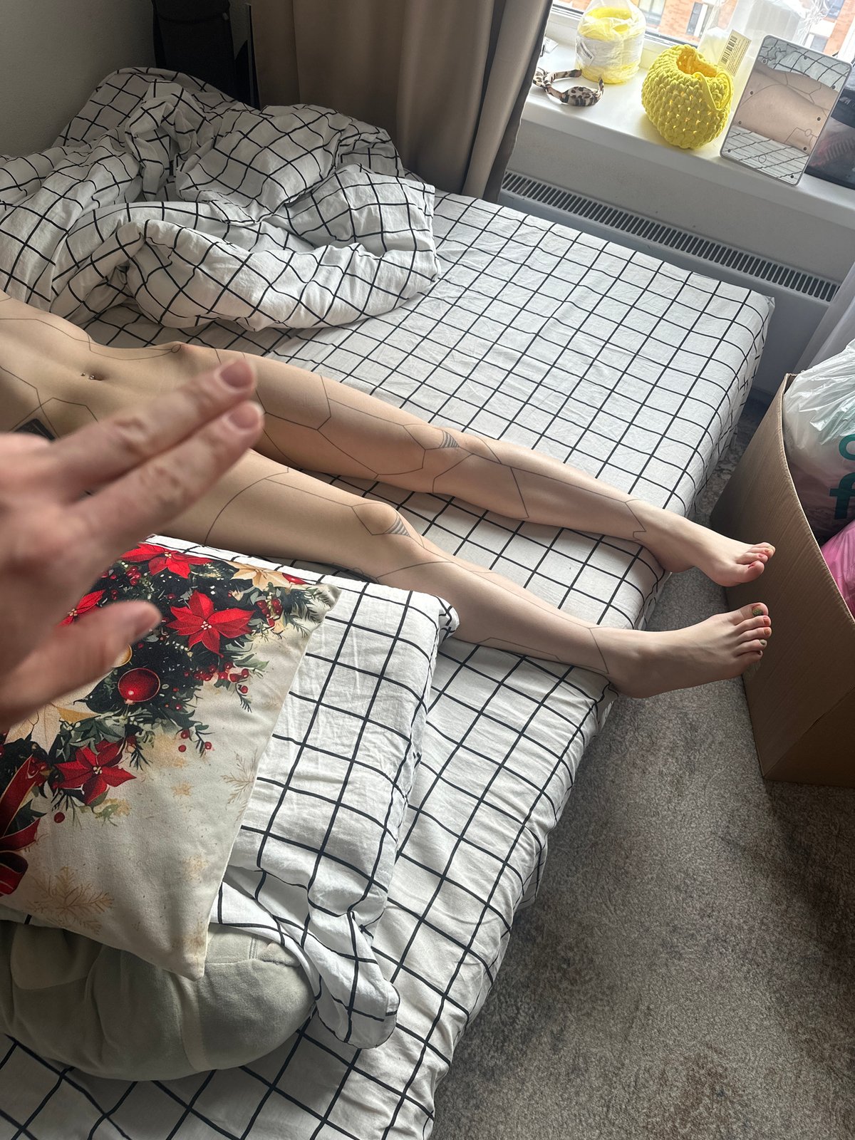 Person with geometric tattoos rests on checkered bed in Lyubertsy
