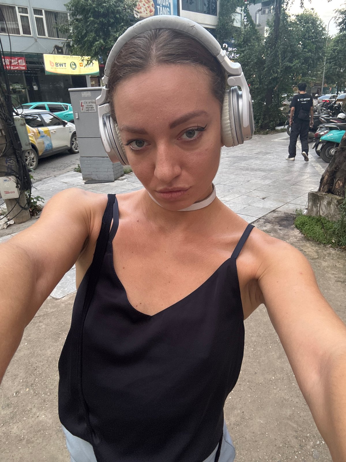 Hanoi street corner: retail signage, VinFast EVs, everyday city life