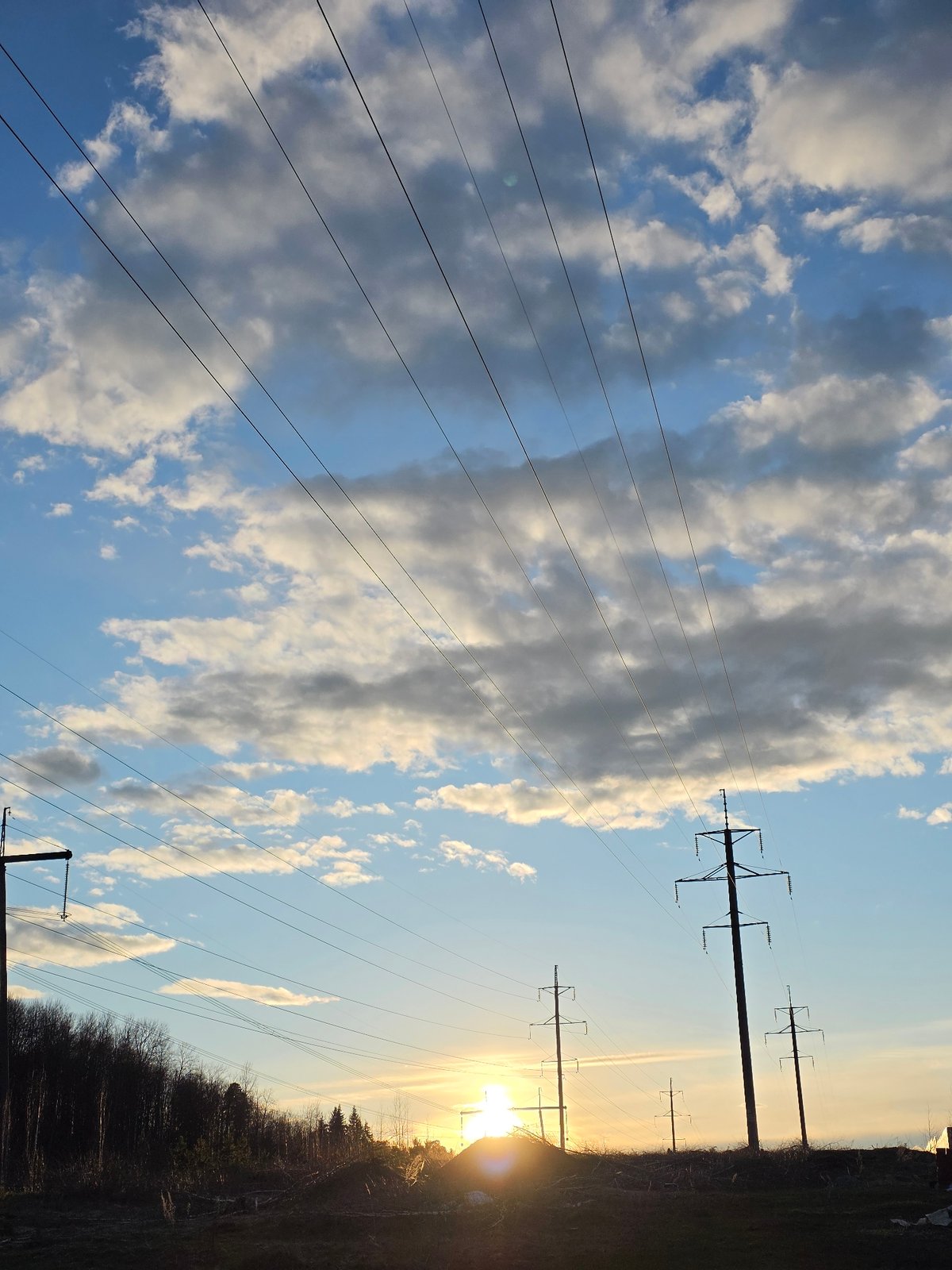 Sky scene with clouds, power lines, low sun observed