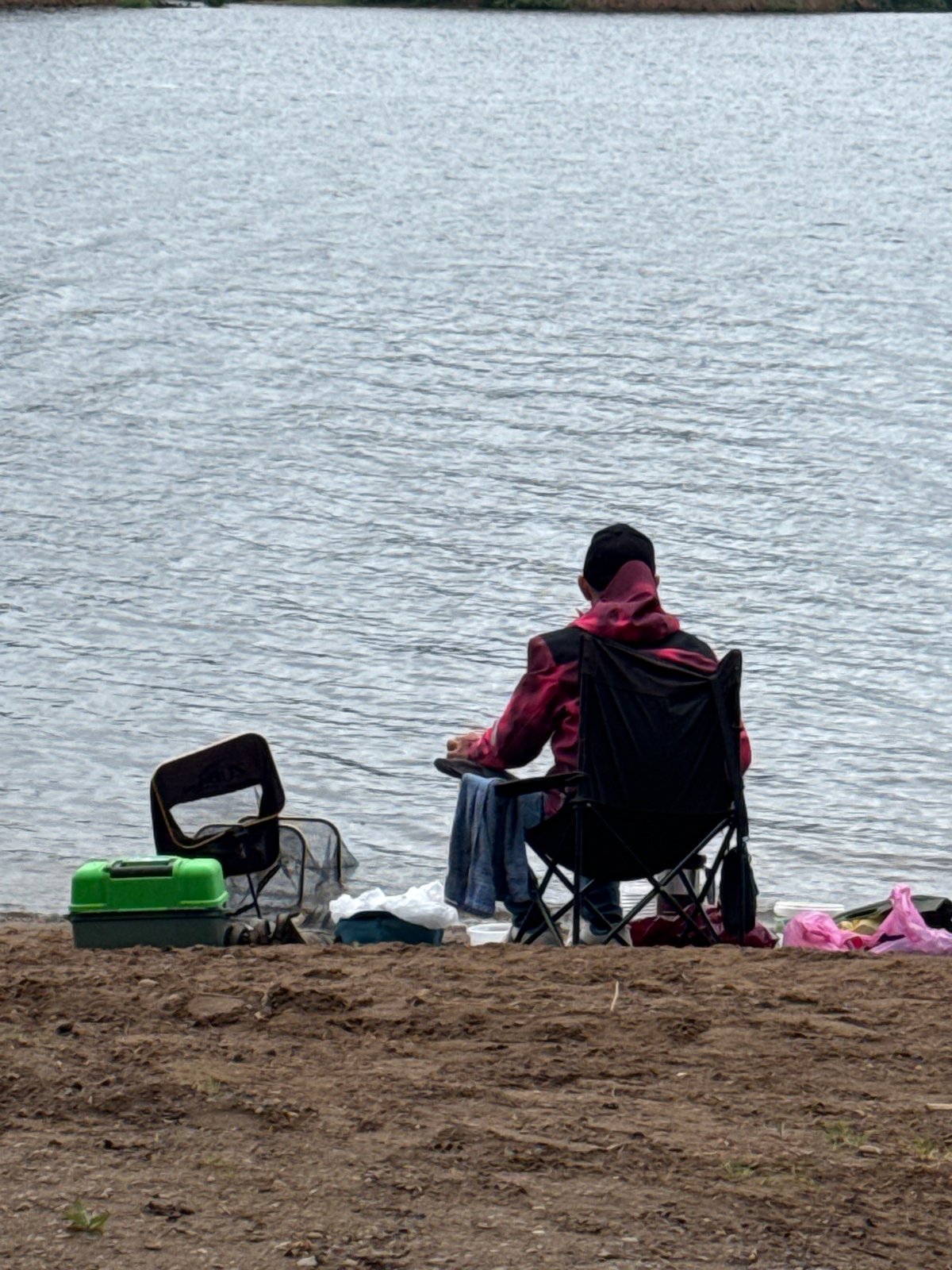 Person sits by industrial waterfront in Chaikovsky, Russia dawn