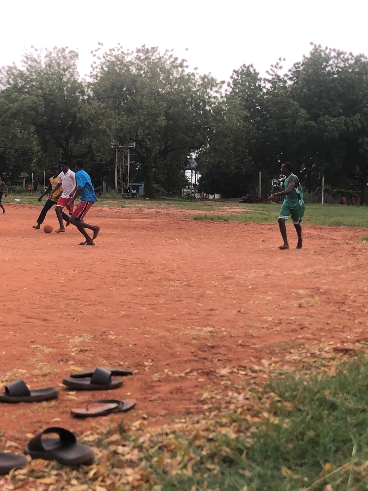 Young men play casual soccer on dirt field in Nigeria