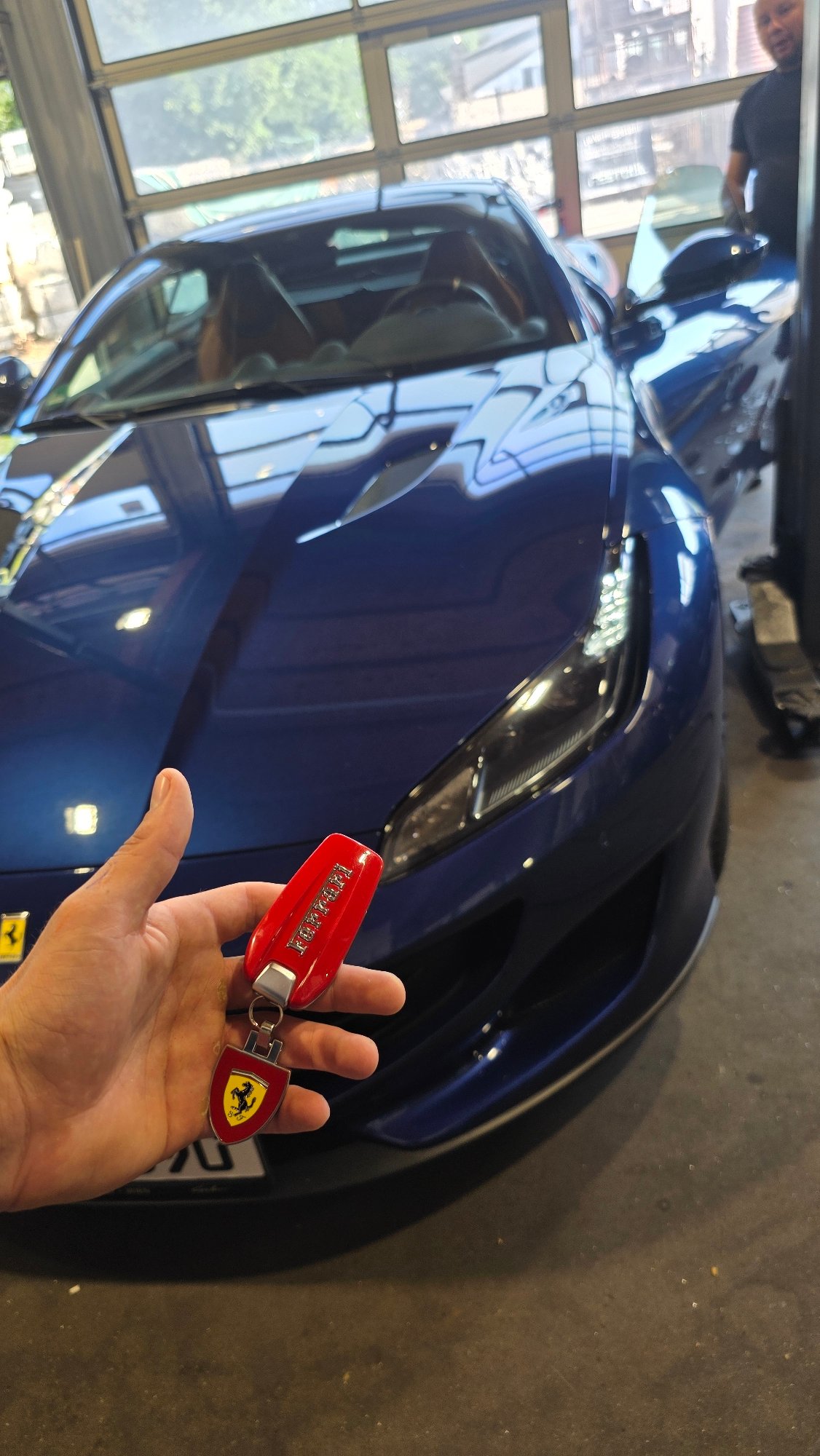 Blue Ferrari gets workshop attention alongside a black BMW SUV.