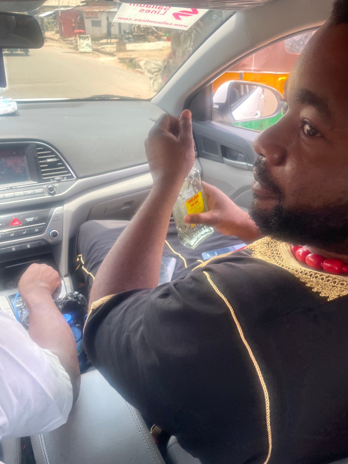 Man in traditional robes pours yellow liquid in Jos
