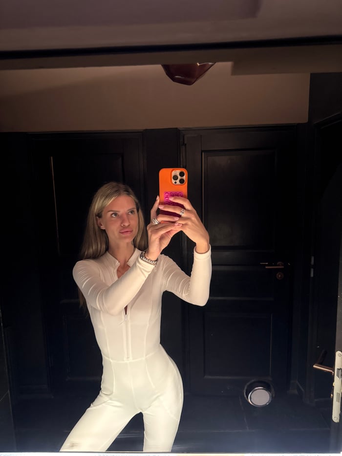 Woman takes mirror selfie in white jumpsuit in Berlin