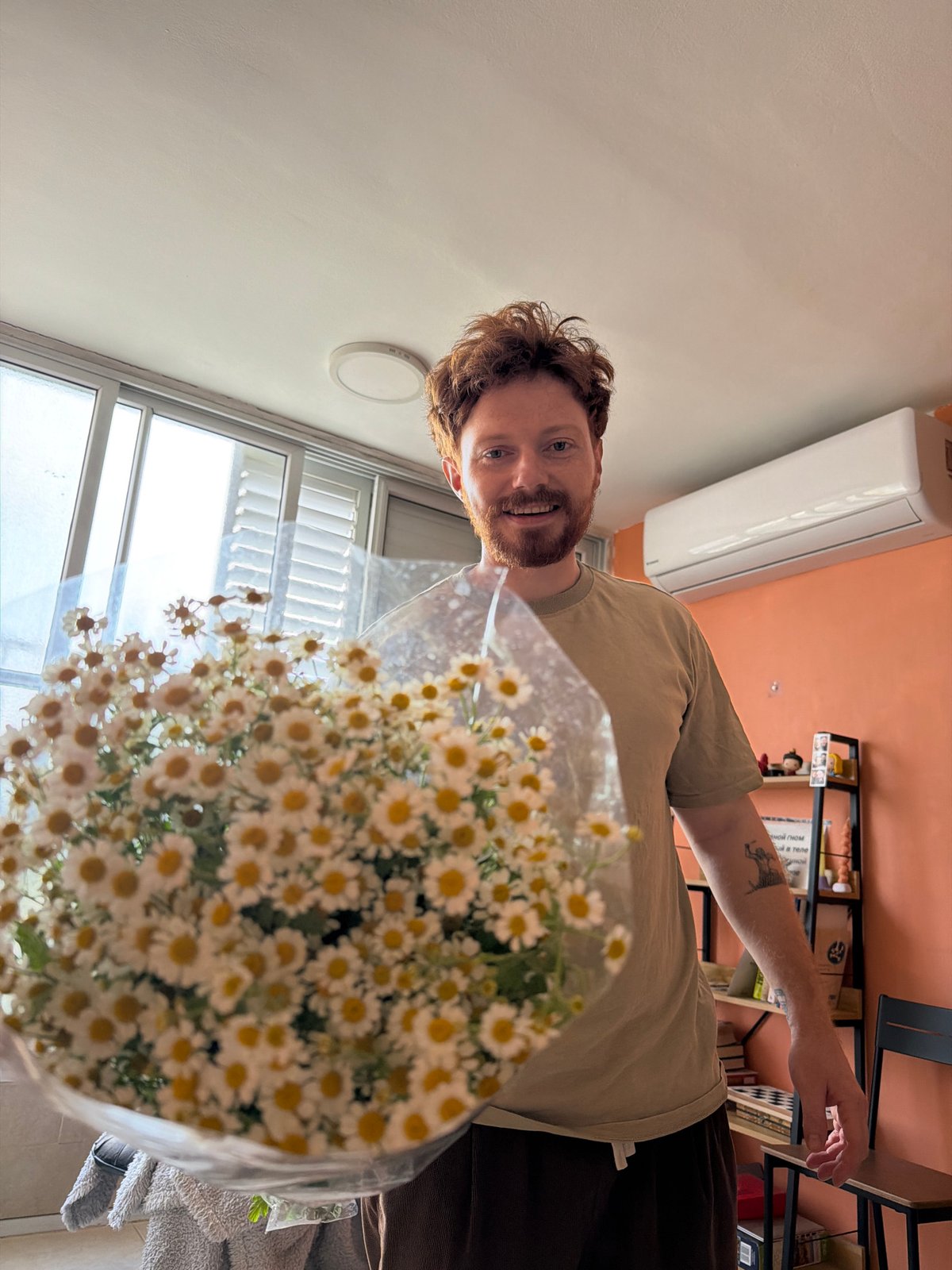Man holds daisy bouquet indoors in Tel Aviv