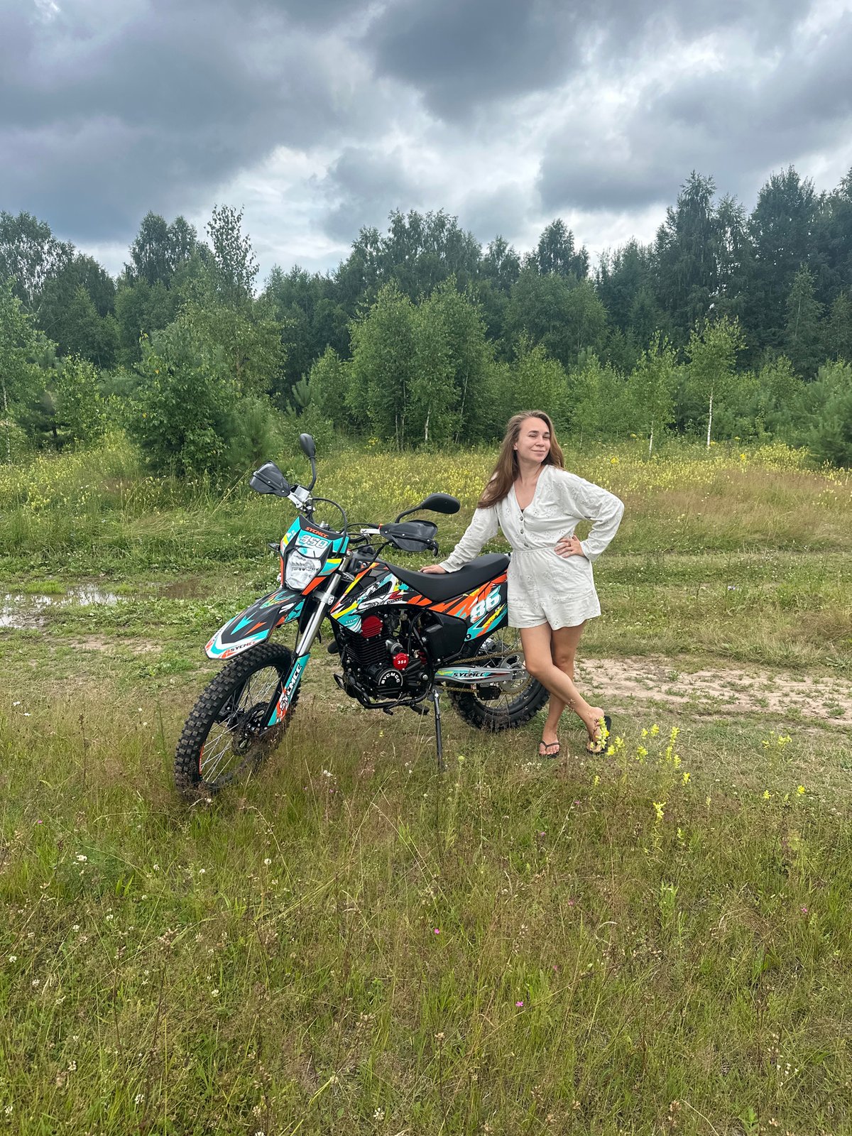 Posing with dirt bikes in a grassy Russian field