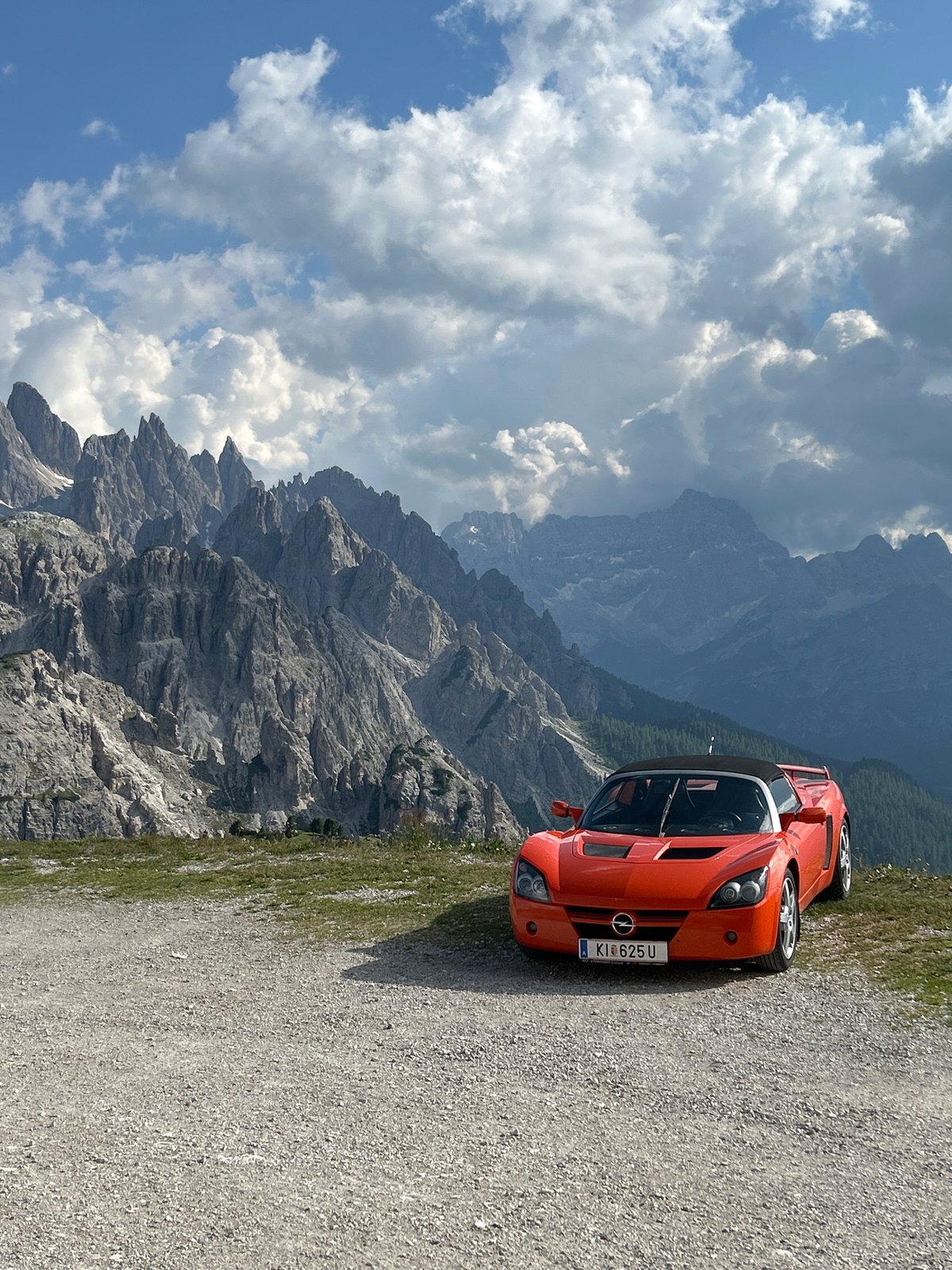 Orange Opel GT parked against sweeping mountain valley views